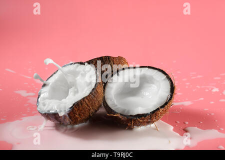 Metà di cocco fresco e splash di latte sul colore di sfondo Foto Stock