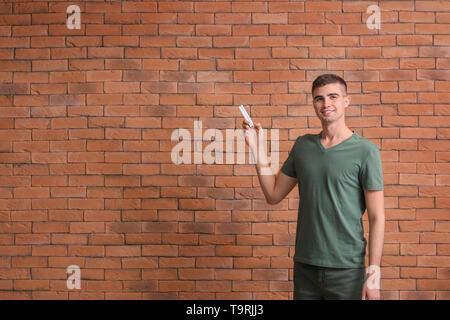 Giovane uomo di accendere il condizionatore d'aria contro Sfondo mattone Foto Stock