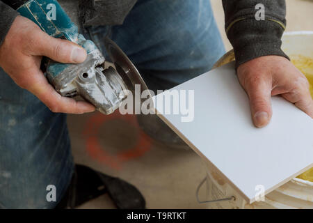 L'uomo lavoratore professionale piastrella di taglio con sega circolare su elettrico ristrutturazione bagno Foto Stock