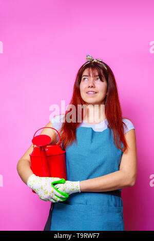 Foto di felice fioraio brunette donna che guarda verso l'alto con annaffiatoio in mano Foto Stock