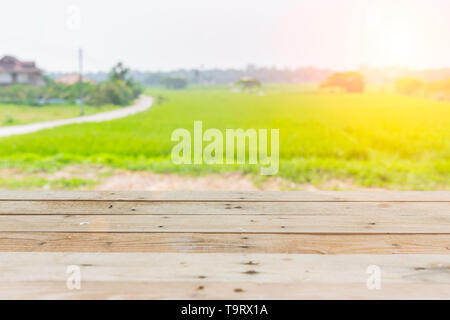 Vista del paese di riso campo verde con tavolo in legno top primo piano spazio per la pubblicità lo sfondo Foto Stock