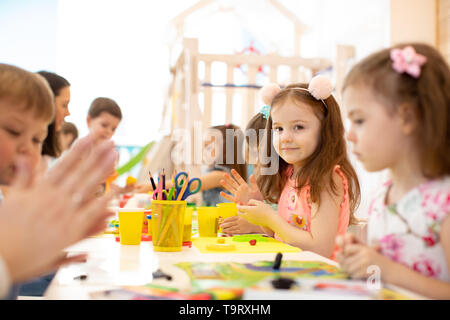 Kindergarten bambini facendo arti e mestieri con insegnante nel centro diurno Foto Stock