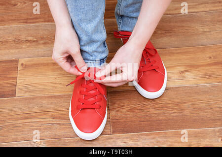 Ragazza di legatura sui lacci delle scarpe da ginnastica. In camera. Close-up. Foto Stock