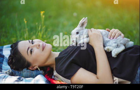 Bella coppia donna asiatica si posa sulla terra e abbracciando un coniglio Foto Stock