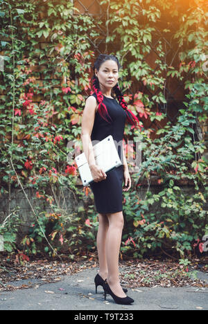Bella asiatica Business donna in posa con il computer portatile per esterno Foto Stock