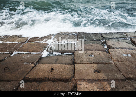 Dark calcestruzzo blocchi frangiflutti con acqua di mare tempestoso, Egitto Alessandria, Egitto Foto Stock