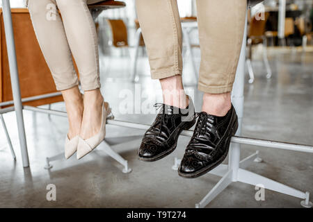 Elegante business giovane seduti al bar, vista sulle loro gambe sotto il tavolo Foto Stock