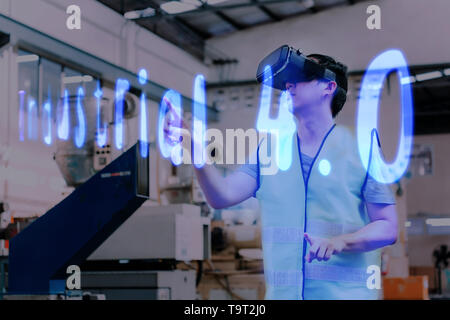 Fabbrica e manfacturing engieering Lavoratore che indossa VR goggle auricolare toccando Industrial 4.0 testo sulla realtà virtuale Foto Stock