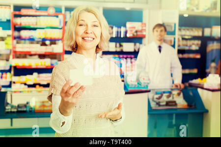 Sorridente maturo paziente femmina l'acquisto di medicine in farmacia Foto Stock