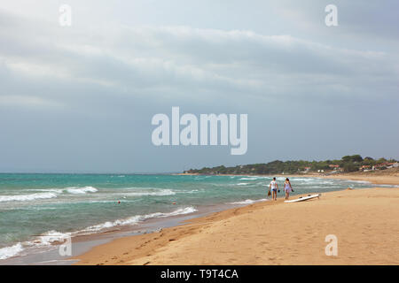 Estate vista mare con spiaggia sabbiosa, onde nella giornata di sole. Vini spumanti Sciabordare di onde sulla spiaggia. Due ragazzi a piedi lungo la riva. Viaggi e vacanze Foto Stock