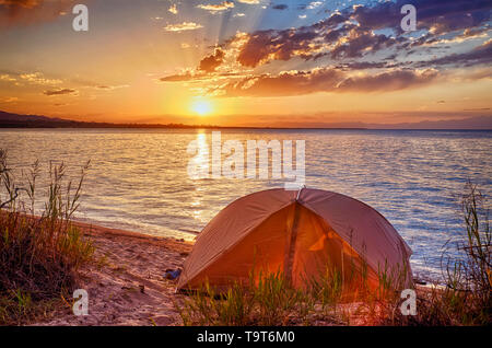 Tenda sulla riva del lago. L'orario del tramonto. Foto Stock