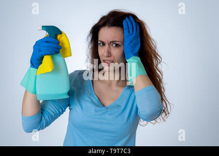 Giovani belle sconvolto casalinga donna tenendo la benna mop spray per la pulizia di sensazione ha sottolineato stanco e deluso in compiti domestici e i ruoli di genere conc Foto Stock