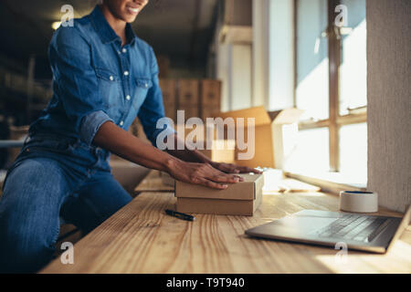 Titolare di una piccola azienda di imballaggio di una scatola per la spedizione al cliente online. Imprenditore femmina lavorando su ordini online. Foto Stock