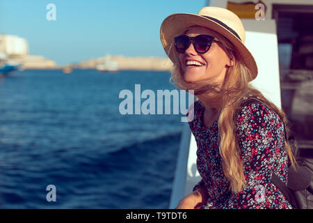 Felice bionda donna mediterranea stupiti dal panorama su una nave da crociera Foto Stock