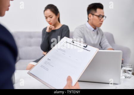 Giovani arrabbiati paio di investitori imbrogliati holding papers sostenendo con maschio agente immobiliare, defraudato gli acquirenti di proprietà di proteggere i loro diritti, troppo Foto Stock