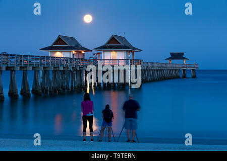 Fotografi catturare l'impostazione luna piena e la mattina presto twilight oltre il Molo di Napoli, Naples, Florida, Stati Uniti d'America Foto Stock