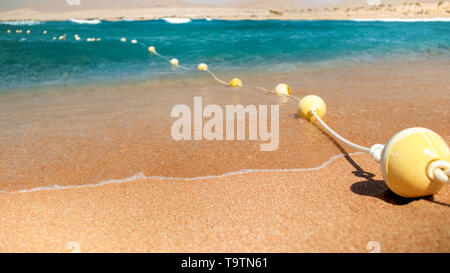 Primo piano immagine di plastica boe galleggianti collegati in linea con fune sdraiato sulla spiaggia del mare. Tiro perfetto per illustrare vacanze estate vacanza al mare. Foto Stock