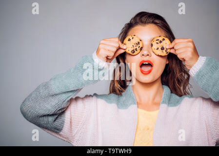 I cookie sono in modo semplice e divertente. Bella ragazza che coprono gli occhi con i cookie. Ragazza carina per divertirti con i cookie. Stile panificio pezzetti di cioccolato Foto Stock