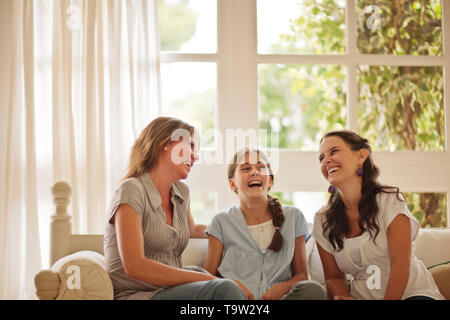 Due sorelle e la loro madre ridere insieme sul divano. Foto Stock
