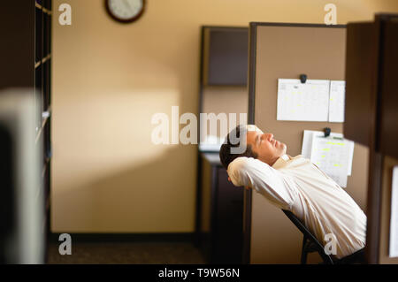 Imprenditore tenendo fuori tempo di mentire indietro sulla sedia. Foto Stock