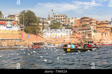 Il turista a godere di un giro in barca sul fiume Gange con vista della antica città di Varanasi architettura e gli uccelli migratori sul fiume Gange Foto Stock