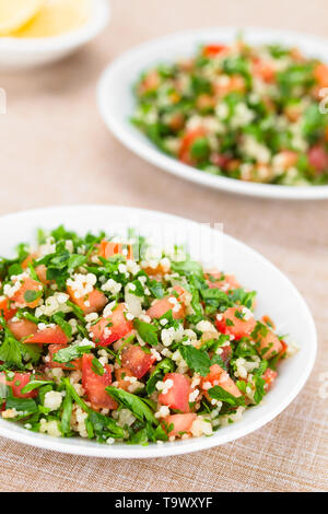 Vegano fresco tabulé insalata di pomodoro, prezzemolo, cipolla e cuscus su piastre (fuoco selettivo, la messa a fuoco di un terzo nell'insalata) Foto Stock