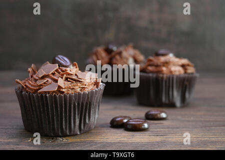 Tortini di marrone con burro di cacao crema, scaglie di cioccolato e chicchi di caffè in legno rustico, spazio copia selezionata, focus, profondità di campo ridotta Foto Stock
