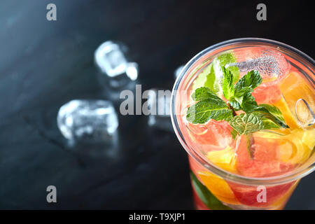 Detox lemonade con succo di pompelmo e fettine di arancio con agrumi freschi e di ghiaccio su un nero lo sfondo di legno. vista da sopra. bevanda rinfrescante. Foto Stock