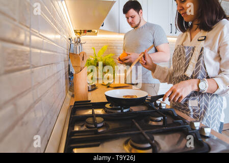 Accoppiare la cucina insieme alla cucina. friggere le frittelle di taglio. arancione stile di vita domestica Foto Stock