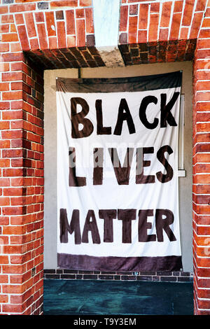 Un nero vive questione banner è incorniciata da un arco in mattoni. Foto Stock