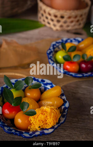Thai dessert su una piastra di bianco e strisce blu poste sul tavolo di legno sono un oggetto simile, forcella, pandan, noce di cocco, le uova nel paniere e golden clot Foto Stock