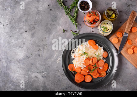 Piastra con gustosi cavolo fermentato e la carota sulla tabella grigia Foto Stock