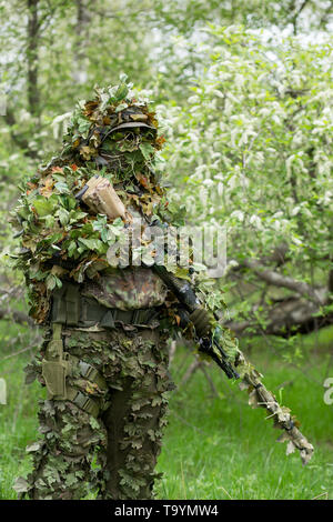 Ritratto di un uomo militare in camuffamento vestiti con un'arma sulla sua mano nella natura d'estate. Esercito, militari, soffice come l'aria, hobby, concetto di gioco Foto Stock