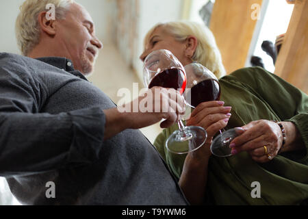 Close-up di coniugi mantenendo i bicchieri di vino rosso in mani Foto Stock