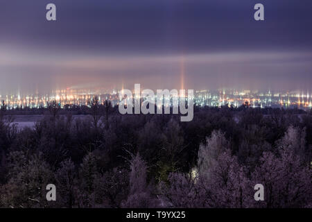 Notte paesaggio invernale con pilastri di luce fenomeno atmosferico. Foto Stock