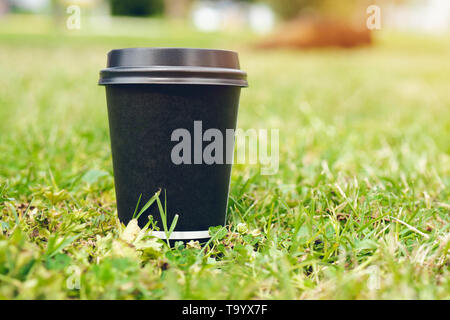 Carta nera tazze di caffè per andare sull'erba. Luogo ideale per il tuo testo o logo su tazze. Foto Stock