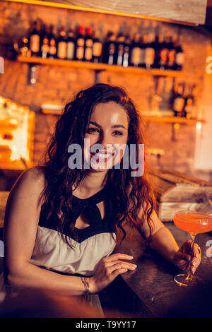 Bella donna sorridente mentre si parla con un amico in bar Foto Stock