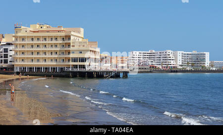 El Medano, Tenerife, Isole Canarie, Spagna - 27 Marzo 2019: vista della spiaggia vulcanica verso il resort hotel, ristoranti e terrazze Foto Stock