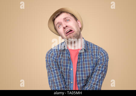 Triste uomo in estate hat cercando sconvolto pronto a piangere, con disperata expresion del viso Foto Stock