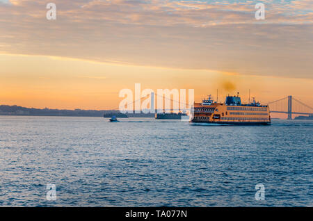 Vista di Staten Island Ferry Crossing New York bay all alba di un giorno d'inverno. Verrazano Bridge è visibile in background. Foto Stock