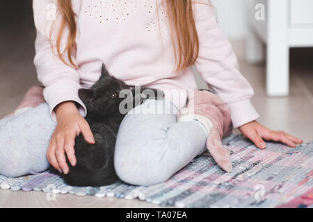 Carino gattino assonnato giacente sul baby girl mani closeup. L'amicizia. Foto Stock