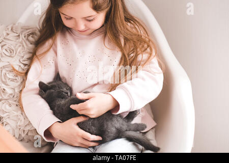 Sorridente ragazza bambino 3-4 anni dorme holding gattino in camera vicino. L'amicizia. Infanzia. Foto Stock