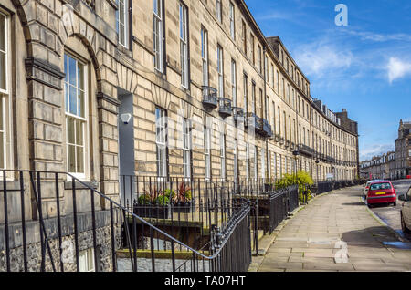 Case a schiera lungo una pavimentazione di pietra nel centro di Edimburgo sotto il cielo blu su un inizio giornata di primavera Foto Stock