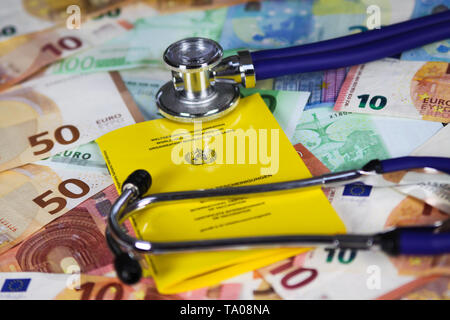 Medical vaccinazione il concetto di costo - lo stetoscopio e il giallo del certificato internazionale di vaccinazione su Euro carta moneta banconote Foto Stock