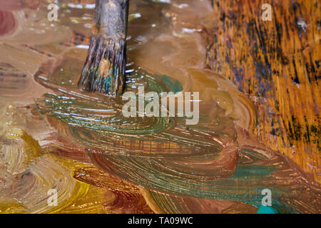 Immagine creativa, artista della tavolozza con vernici a olio e spazzole, close-up, vecchia tavolozza in legno, vernici di colori differenti, close-up del pennello dell'artista, Foto Stock