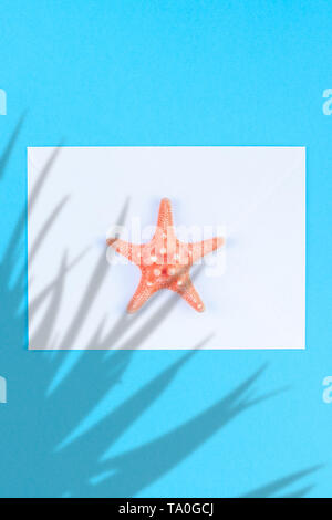 Piatti creativi concetto laici di viaggio estivo per le vacanze. Vista dall'alto di conchiglie e stelle marine sul turchese sfondo blu con postcard mock up e copia s Foto Stock