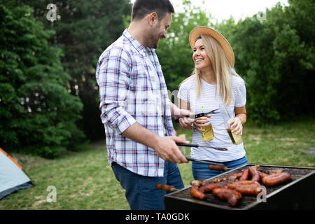 I giovani di sesso maschile e femminile giovane la cottura barbecue in natura Foto Stock