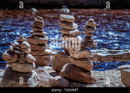 Piramide di pietre sulla spiaggia di ciottoli che simboleggiano la stabilità, zen, armonia, equilibrio.Piramidi di pietra. Foto Stock