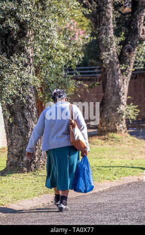 Johannesburg, Sud Africa - Un nero non identificato donna cammina a casa dal suo lavoro come un lavoratore domestico nella città immagine in formato verticale Foto Stock