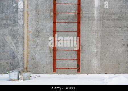 Vista di rosso la scala di metallo al di fuori di un edificio in cemento Foto Stock